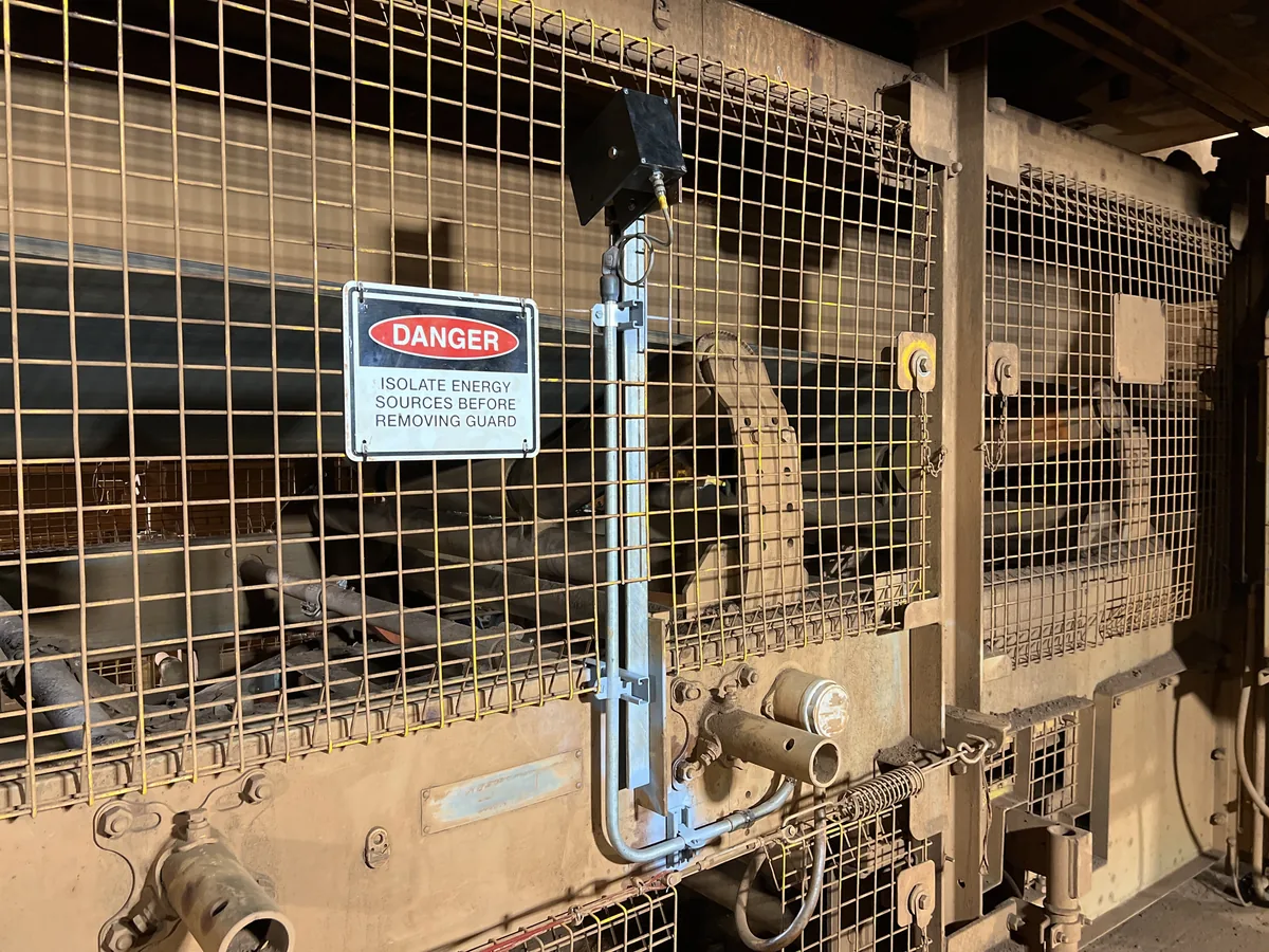 Sensor mounted through the conveyor guard, reading the belt edge