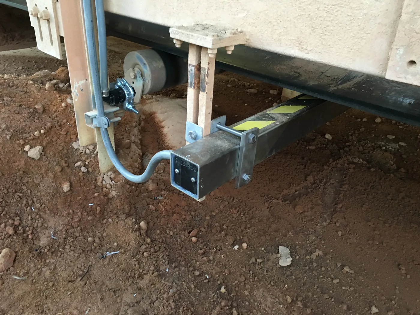 End of the Belt Scanner MF scanner clamped to a conveyor cross member with stainless mounting plates and a flexible conduit run.